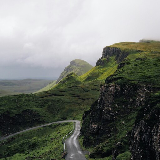 A winding mountain road through misty green hills in the Irish countryside