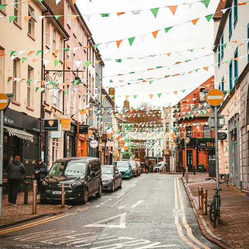 An Irish town street decorated with green, white and orange bunting
